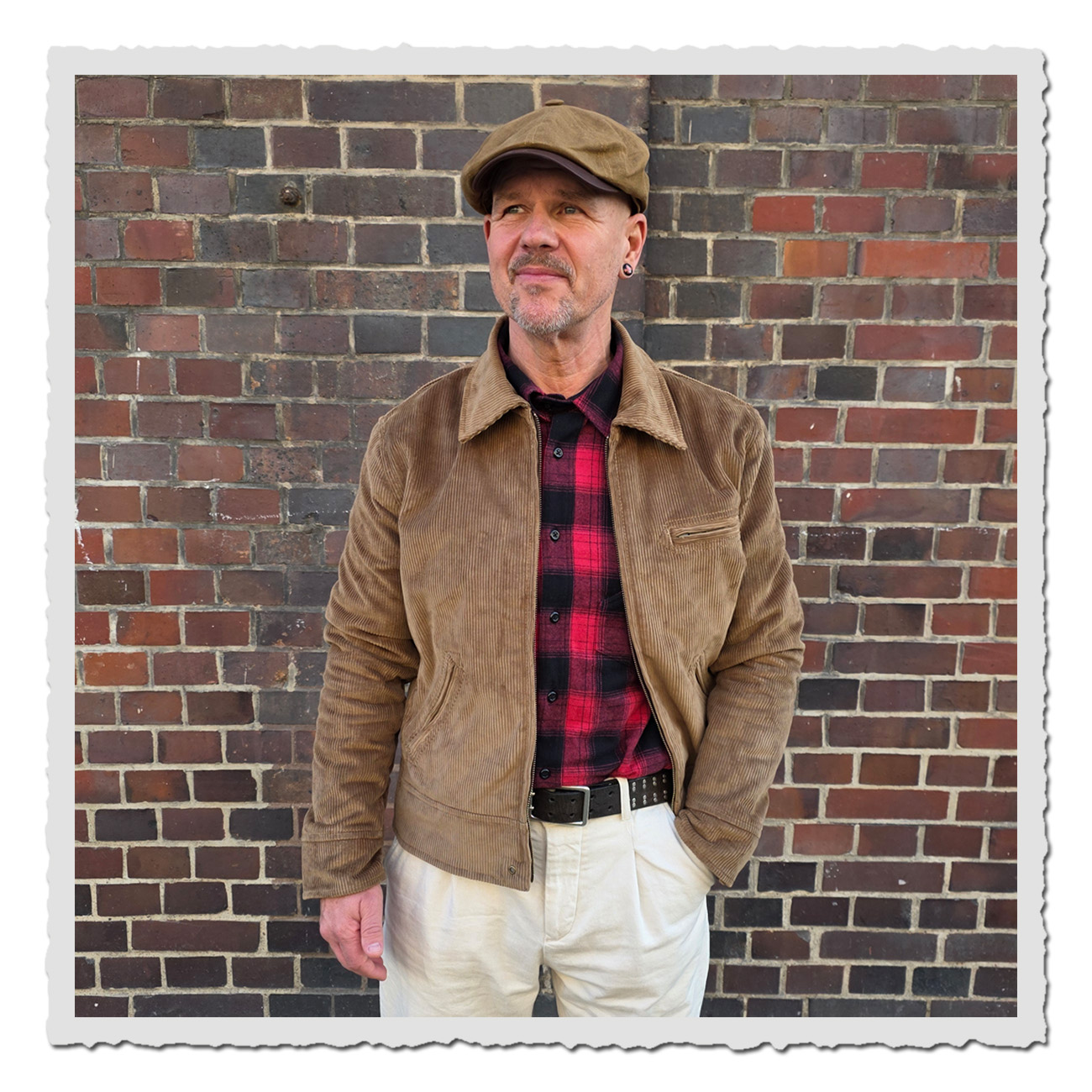 Mann vor Ziegelwand trägt Pike Brothers 1932 Roadster Jacket Light Brass Cord – klassische Cordjacke im Vintage-Stil